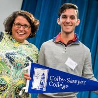 Deposited students holding a Colby-Sawyer banner next to his family